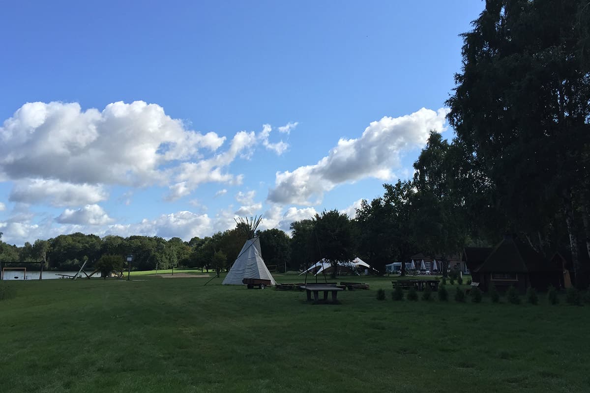 Wiese mit Tipi und Picknicktischen nahe dem Ufer des Irenensees